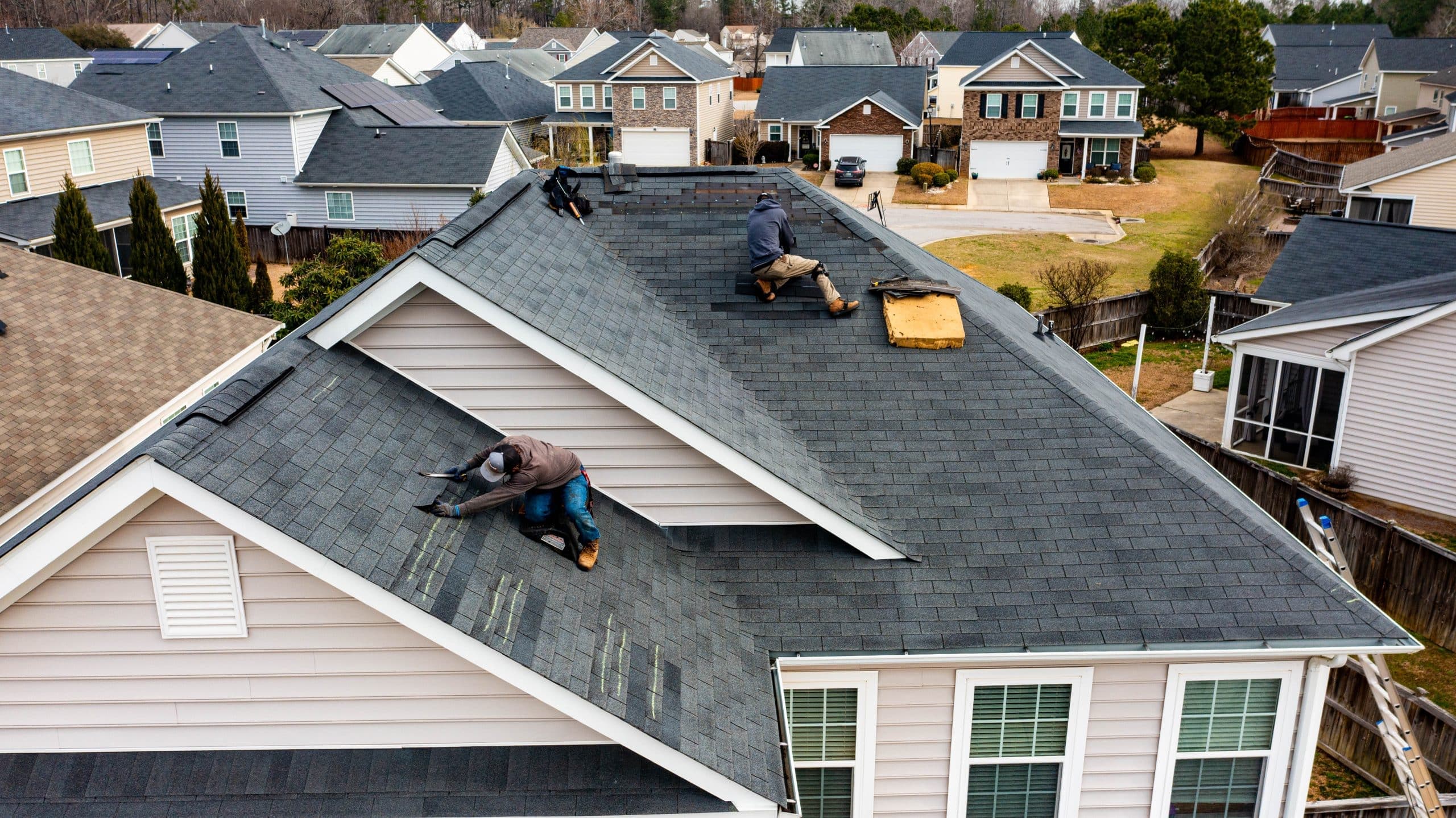 Aerial drone view of a Sands Roofing crew installing shingles on a residential home